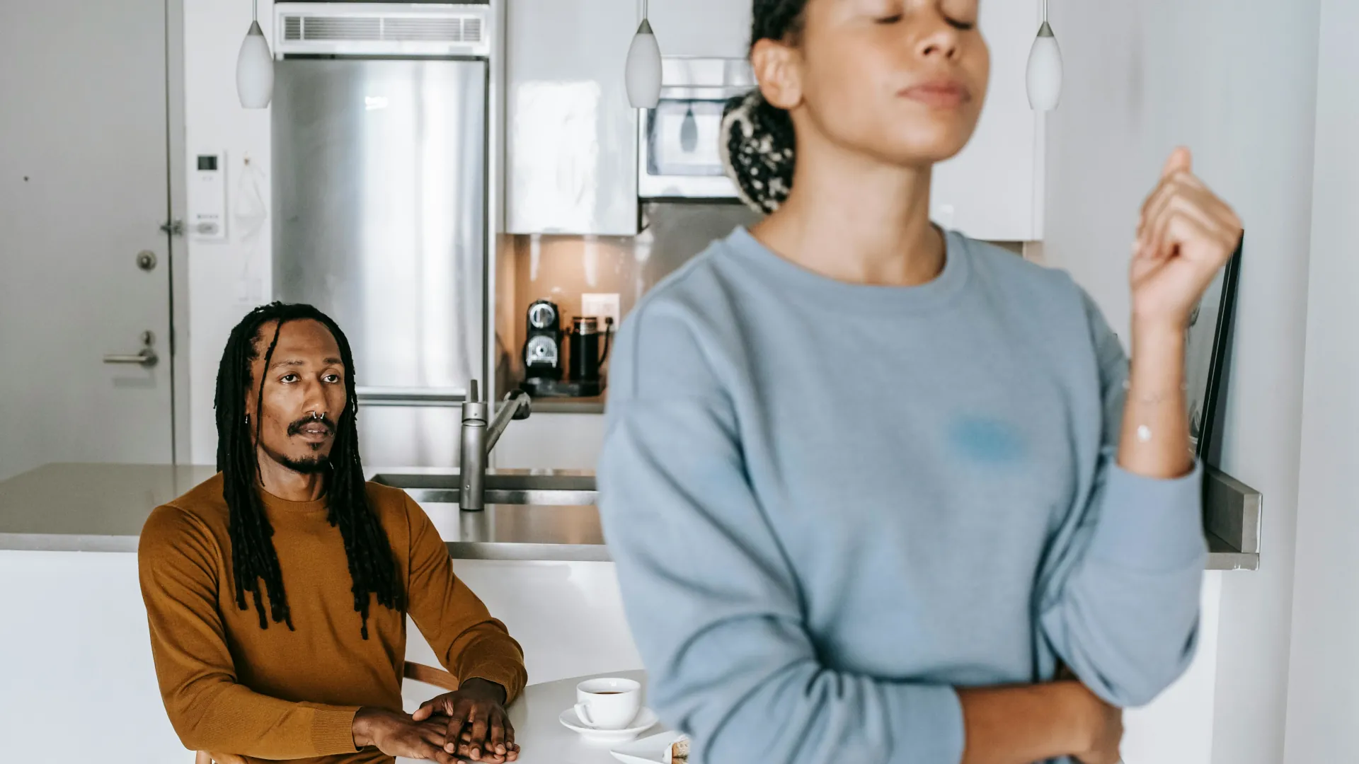 A couple having a heated argument. The woman is trying so hard to contain her anger. The man appears genuinely sorry and is staring in disbelief.
