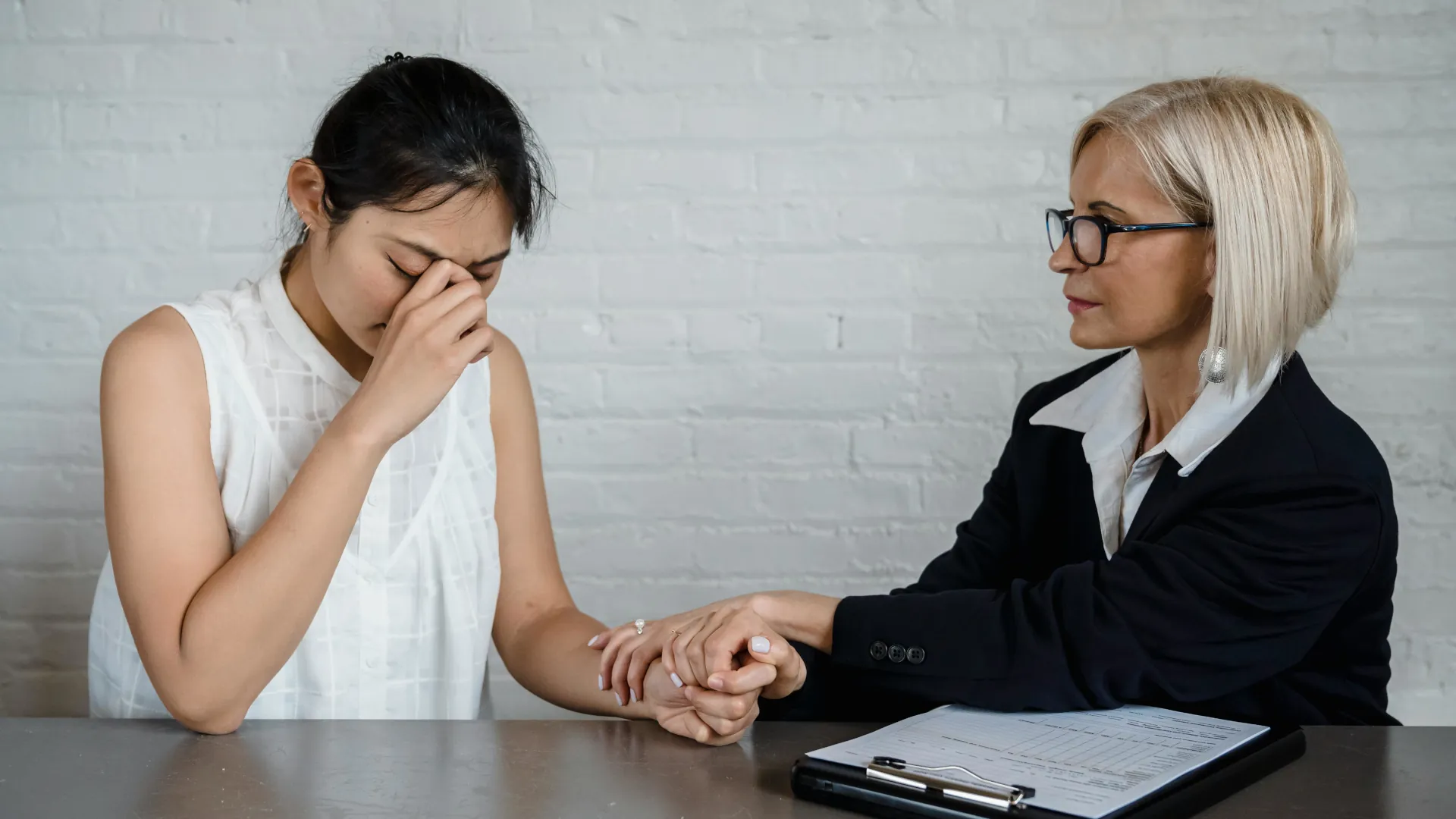 A young female who is upset is quietly being comforted by a counsellor.